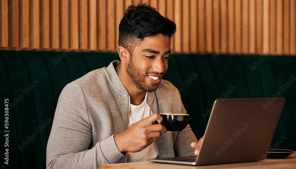 Poster .. Happy young mixed race man sitting at a table in a cafe drinking coffee and using a laptop alone. One hispanic businessman sitting in a restaurant sending an email while working on a laptop.
