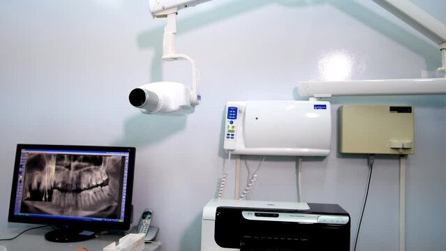 Dentist examines X-ray panoramic patient jaw picture attentively. Young woman clicks on monitor and makes problematic place closer