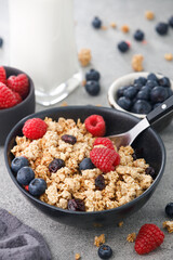 Tasty granola with berries and milk on stone background, close up. Healthy breakfast.