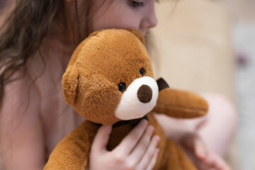 A girl, a brunette of seven years with a teddy bear in her hands.