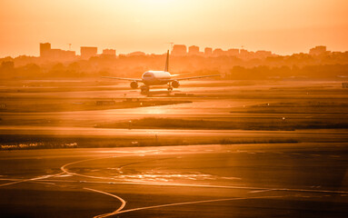 Fototapeta premium A passenger flight running on the track in Sydney airport in the sunset