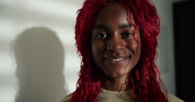 Portrait of a happy carefree african american woman with red colored hair, smiling to the camera