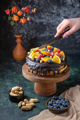 front view yummy chocolate cake with fruits getting cut by female on dark background dough pie sweet biscuit cake dessert sugar
