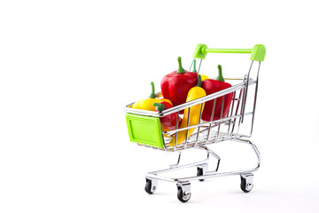 A shopping cart full of different small and large, red and yellow, hot and sweet peppers.  The concept of selling and buying food.  Isolated on white background