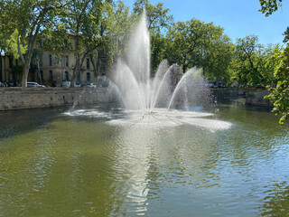 N&icirc;mes, France - 04 19 2023: The Gardens of La Fontaine. View of water jets from the fountain quay.