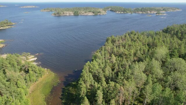 Aerial Drone Footage View: Coastal landscape of Lake Ladoga with islands covered with green forest and indented coastline. Majestic view of the expanse of a large lake. Lake Ladoga, Russia, Europe. 4K