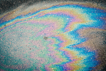 Petroleum fuel spilled on wet asphalt, abstract background.