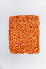 Lens culinaris is scientific name of Turkish Red Lentil legume. Also known as Lentilha Vermelha (portuguese). Top view of grains in a glass. White and blue background.