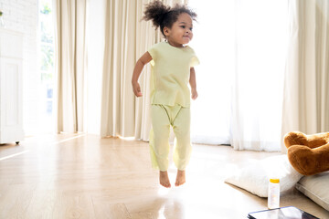 Soft focus African American daughter running dancing in the living room with smile. modern home...