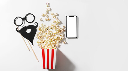 Delicious popcorn, party props and smartphone with blank screen for your design