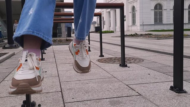 Girl feet dangling in wind above cityscape. Feet view dangling hanging in the air. Children's feet in sneakers and jeans on background of old city. Concept of childhood, fun, carelessness.