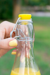 Cropped image of a girl who is holding and opening a bottle of fresh juice outside