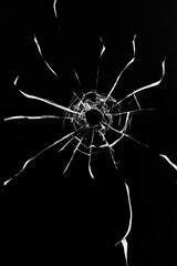 Broken glass shot, crack texture with bullet hole on black background.