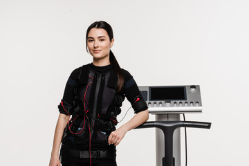 Fit girl in EMS suit on white background. Sport training in electrical muscle stimulation suit.
