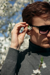 Crop man with flower in hair in spring park on sunny day 