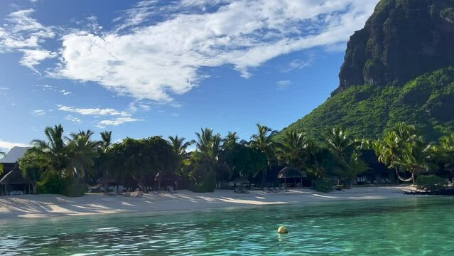 Le Morne beach, view from the the ship. Beautiful turquoise water and exotic nature. Tropical beach with palm trees and white sand blue ocean and beach beds with umbrellas and sun chairs.