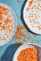 Lens culinaris is scientific name of Turkish Red Lentil legume. Also known as Lentilha Vermelha (portuguese). Top view of grains in a glass. White and blue background.