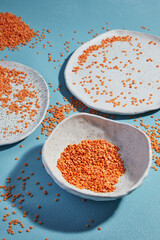 Lens culinaris is scientific name of Turkish Red Lentil legume. Also known as Lentilha Vermelha (portuguese). Top view of grains in a glass. White and blue background.