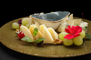 cheese plate featuring a variety of sliced cheeses, grapes, nuts, and honey