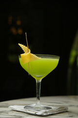 Glass of green cocktail with lemon peel