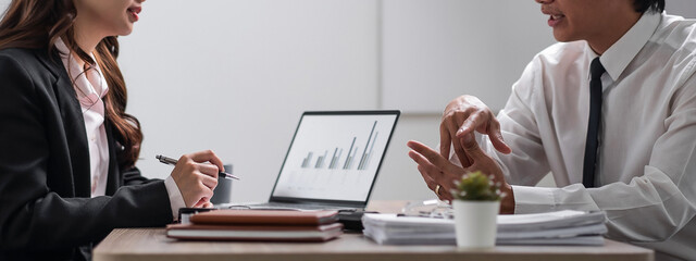 Young confident business people sitting at the office table working analyze on laptop computer with partner. Business concept. Banner design