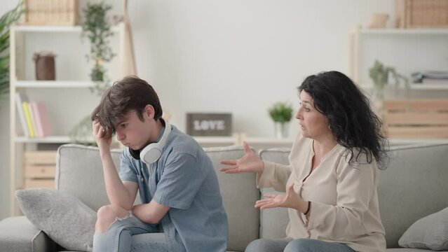 Mother trying to talk to teenager son, who is ignoring her. Frustrated woman scolding teenager boy