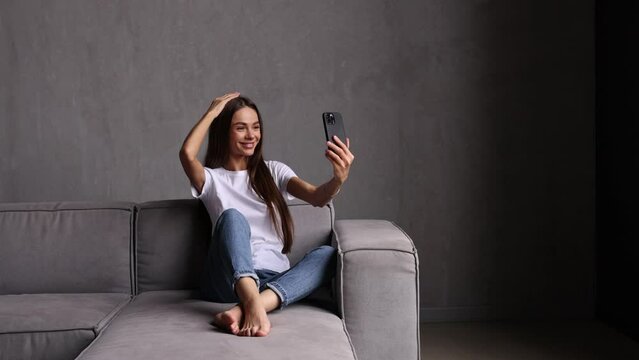 Young woman use phone for video call while sit on the couch