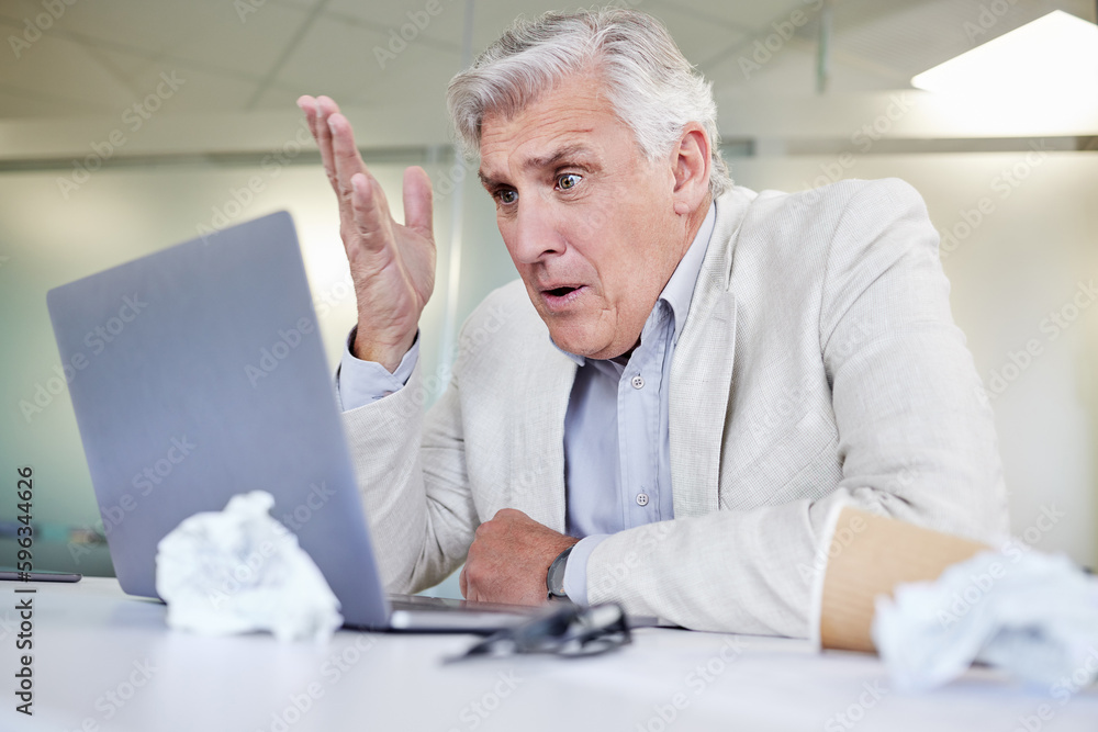 Poster whats going on. shot of a mature businessman looking overwhelmed while using a laptop in an office a