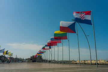  Inernational flags waving in the sky at the belgium coast city Nieuwpoort.  Flags at the belgium coast north sea waving in the wind with a blue sky.  Flags in movement, in flanders, west-vlaanderen.  © robin