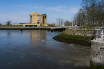 Schilderijen op glas Overview at the Westfront located at city Nieuwpoort at the belgium coast.  River de ijzer with the Koning Albert I monument and a blue sky.  Belgium coast toerism picture.  With the water dam. © robin