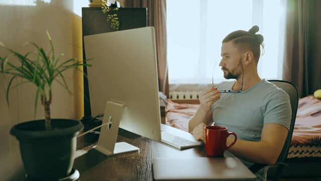 Side view of a young male working at home using a desktop computer.
