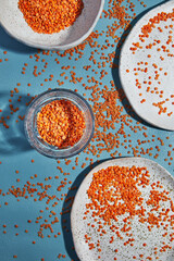 Lens culinaris is scientific name of Turkish Red Lentil legume. Also known as Lentilha Vermelha (portuguese). Top view of grains in a glass. White and blue background.