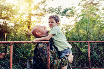 Soldier seturning home and greeted by son. An overjoyed boy is waiting to hug his dad who is...