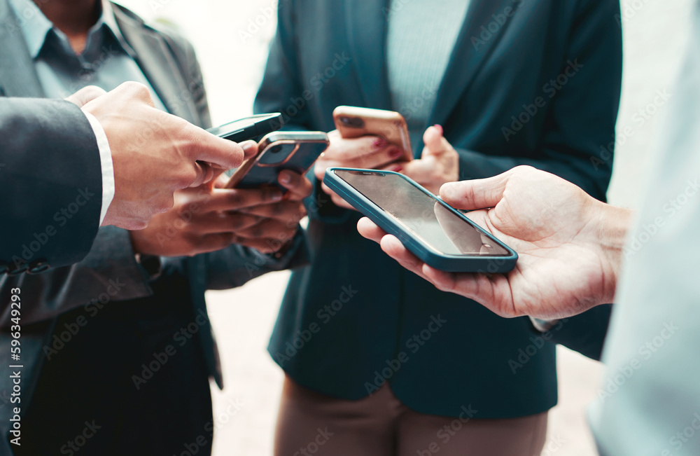 Poster Lets connect. High angle shot of a group of unrecognisable businesspeople using their cellphones while standing in a huddle.