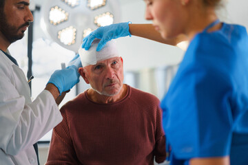 Close-up of doctor and nurse treating injury of senior man.