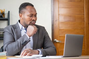 Naklejka premium An African American businessman in a black suit smiling and showing joy at the company's annual profit to build confidence for customers who will invest in the office.