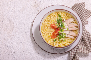 Spicy noodles with beef broth. Hot dish, cutlery, hard light, dark shadow. Stone concrete background