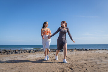 Two sisters hold hands and run at the beach, sister love