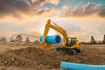 Obraz premium Crawler excavator is digging soil in the construction site and laying pipes with a sunset backgrounds.