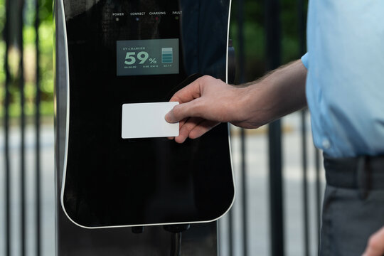 Hand holding credit card to pay public charging station and recharge her electric vehicle, symbolizing progressive lifestyle, combines e-wallet technology and sustainable transportation option.
