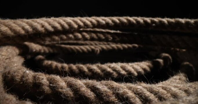 Closeup of nautical rope folded into spiral on black background. Closeup of thick heavy duty rope showing details of threads and fibers