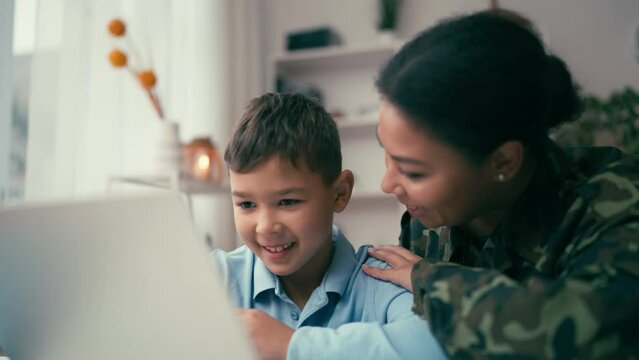 African American woman soldier and her son using laptop to do school homework