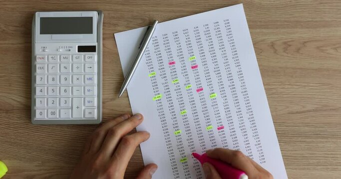Person accountant puts marks pink marker on sheet of paper with printed table of financial numerical data and marked. Numbers and accounting concept