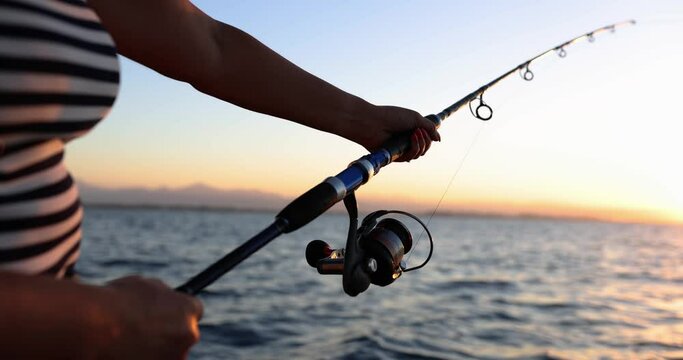 Deep sea fishing reel on boat during sunrise. Tourist fishing from boat