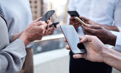 When were connected, everyone stays updated. Cropped shot of a group of unrecognizable businesspeople using their cellphones.