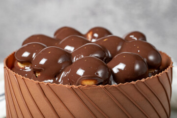 Chocolate covered profiteroles birthday cake. Chocolate cream cake on gray background. Close up
