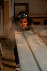 Carpenter woman blow debris and sawdust of wood product from timber in workplace.