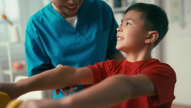 Female rehabilitation doctor working with a child on strengthening arm muscles