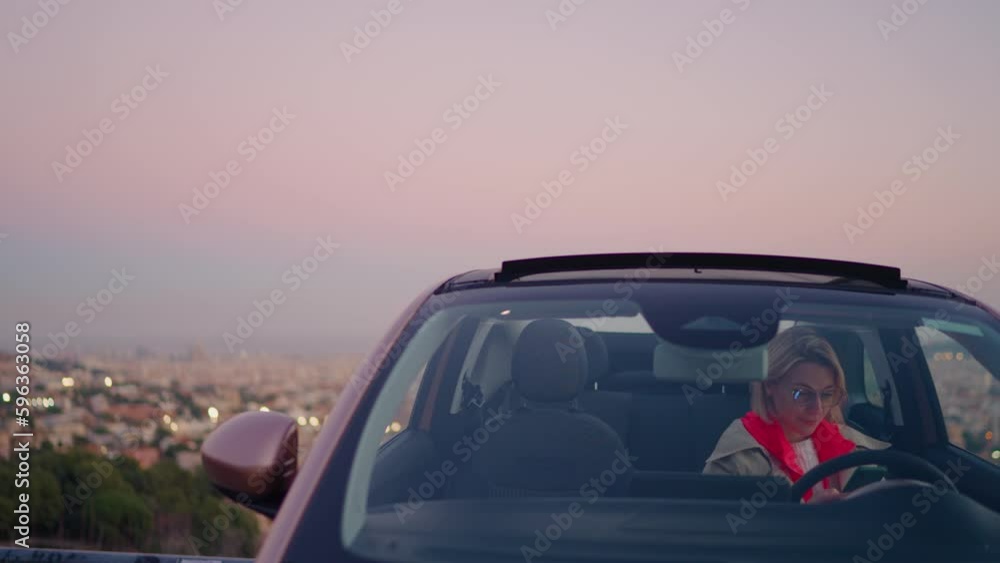 Poster smiling caucasian female driver uses mobile phone device to make a payment while sitting in the car.