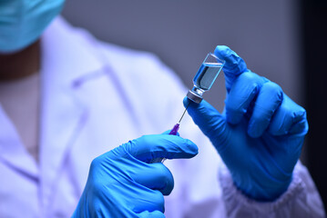 Female doctor wearing blue hand is using syringe to aspirate vaccine from vial. epidemic concept, virus, ,corona, health and medical